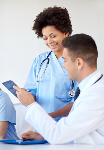 Foto concetto di ospedale, professione, persone e medicina - gruppo di medici felici con computer tablet pc che si incontrano presso l'ufficio medico