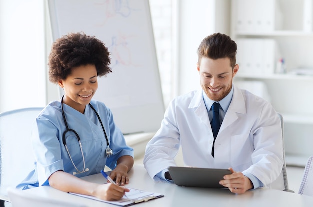 병원, 직업, 사람, 의학 개념 - 태블릿 PC 컴퓨터 회의를 하고 의료 사무실에서 이야기하는 두 명의 행복한 의사