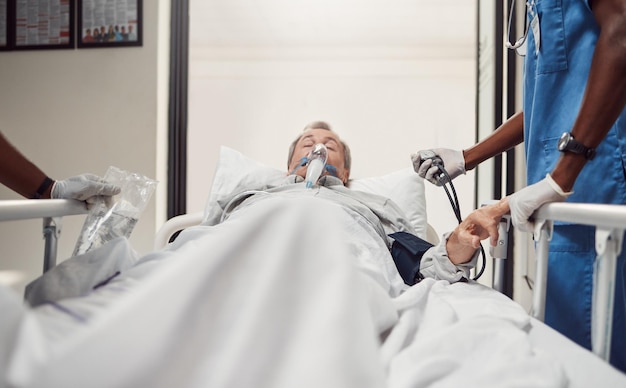 Photo hospital senior patient and doctors for emergency on a bed with oxygen mask for healthcare sick old man with health problem and medical team er or surgery in theater for life insurance and help