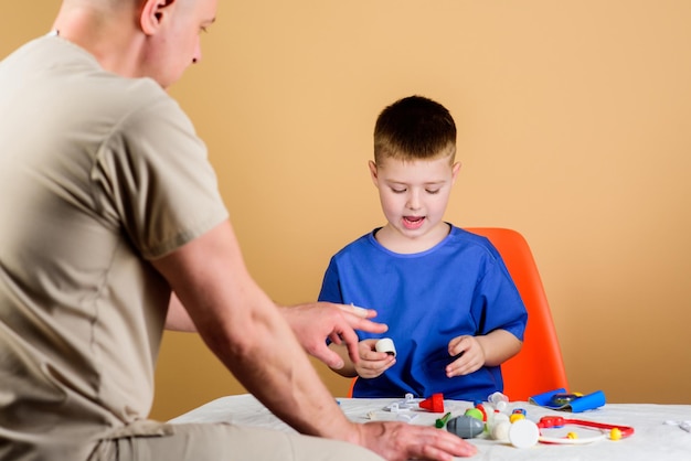 Hospital worker medical service analysis laboratory kid little\
doctor sit table medical tools health care pediatrician concept boy\
cute child and his father doctor medical examination