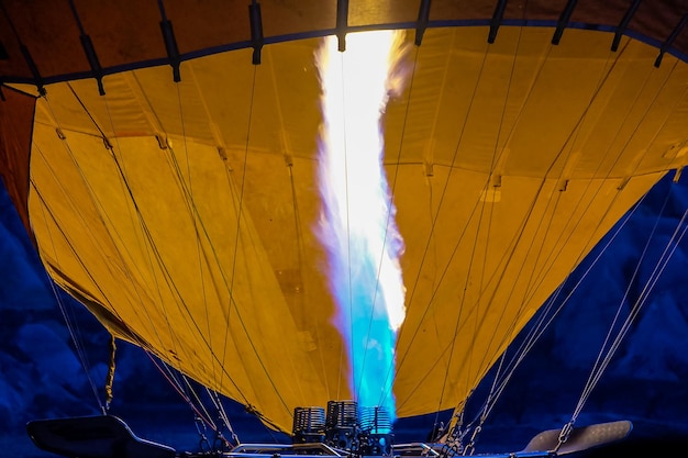 A hot air balloon being hot air filled with flames before sunrise