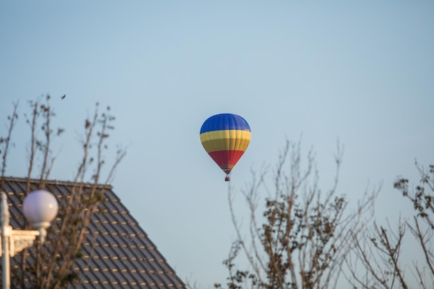 A hot air balloon flies over a house in the sky.