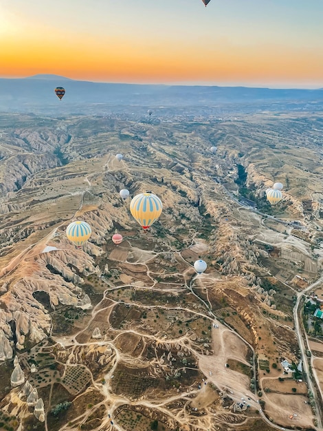 Hot air balloon flying over rocky landscapes in Cappadocia with beautiful sky on background