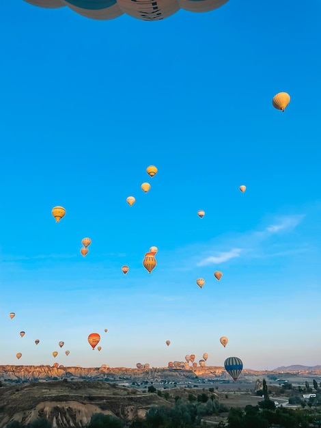 Hot air balloon flying over rocky landscapes in Cappadocia with beautiful sky on background