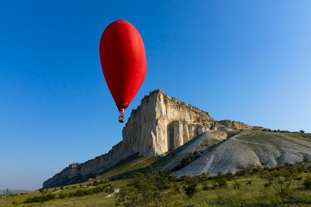 Mongolfiera, palloncino rosso a forma di cuore volante sullo sfondo della roccia bianca. foto di alta qualità