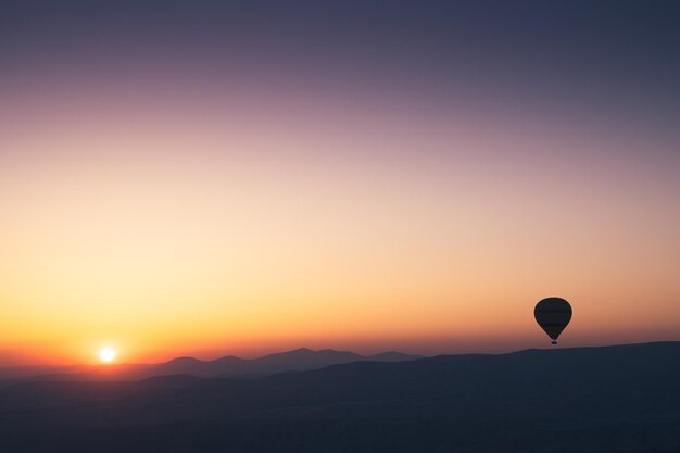 Hot air balloon silhouette with sun rising over the\
mountains