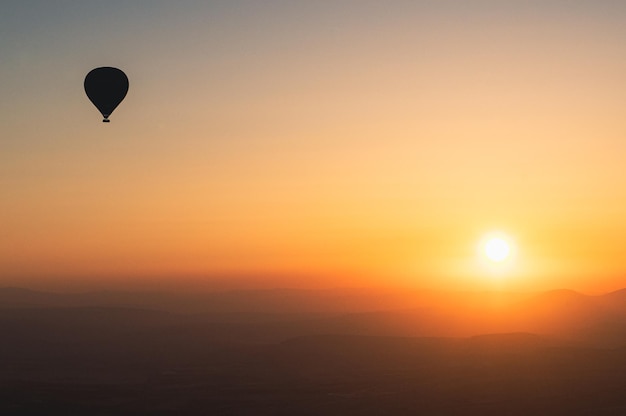 Hot air balloon silhouette with sun rising over the\
mountains