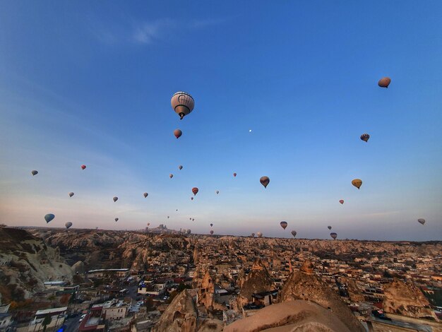 Hot air balloons flying in city against blue sky