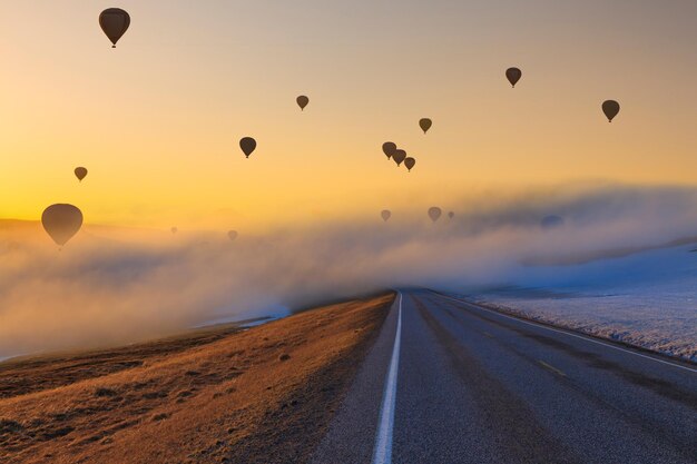 Foto mongolfiere sulla strada al tramonto concetto di percorso e avventura