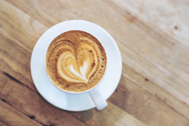 Hot art coffee cappuccino in a cup on wooden table background  