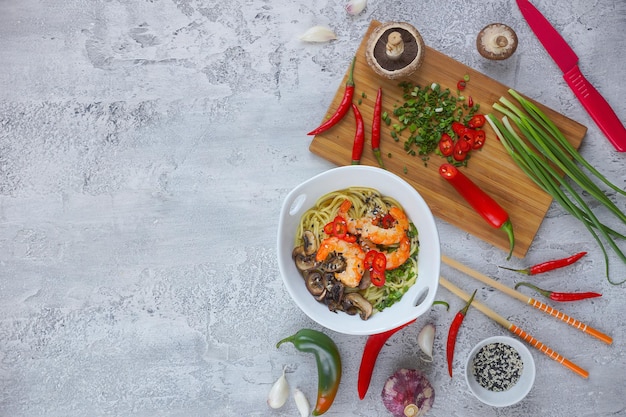 Hot asian wok noodles with shrimps and mushrooms, Preparation ramen, Gray background, Copy space