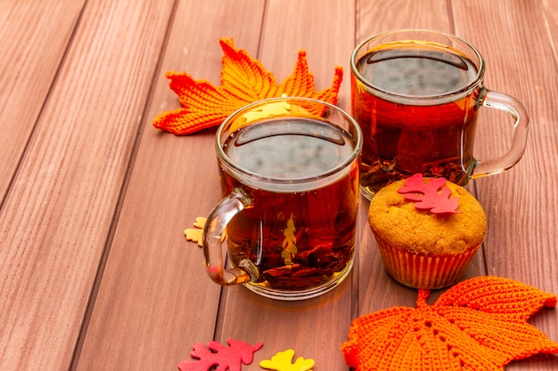 Photo hot autumn drink. black tea with cupcakes, colorful leaves