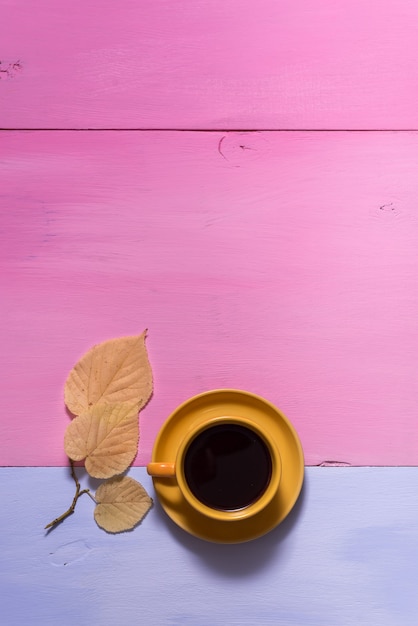 Caldo nero caffè aromatico americano su un vecchio tavolo in legno rosa blu con foglie di autunno