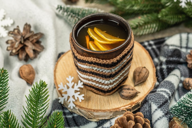 Hot black tea and lemon with winter decor. Cozy sweater, fir tree branches, nuts, snowflakes. Festive seasonal arrangement, good mood concept, rustic style