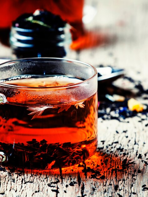 Hot black tea with flowers in glass on vintage wooden background selective focus