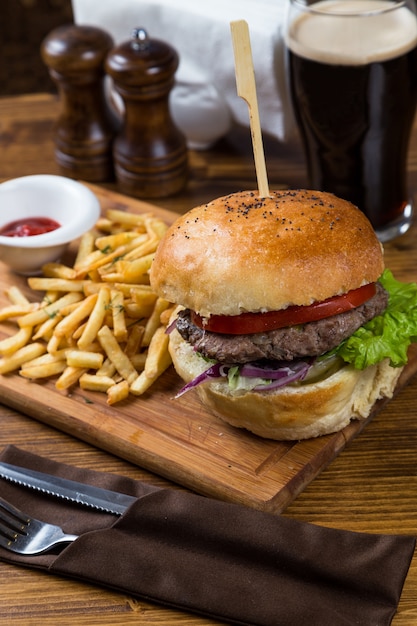 ダークビールと木の板で提供するホットハンバーガー