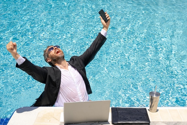 Hot business funny excited office worker with phone business man in suit used phone in beach travel
