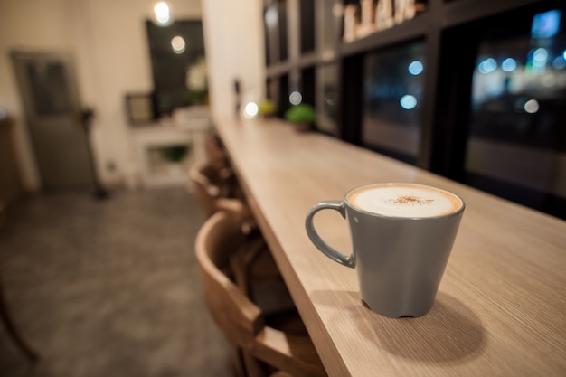 Hot cappuccino in a blue cup, put on a wooden table