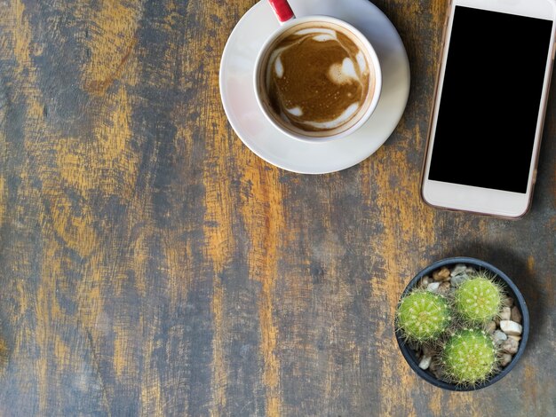 Hot cappuccino and cellphone on old wood top view