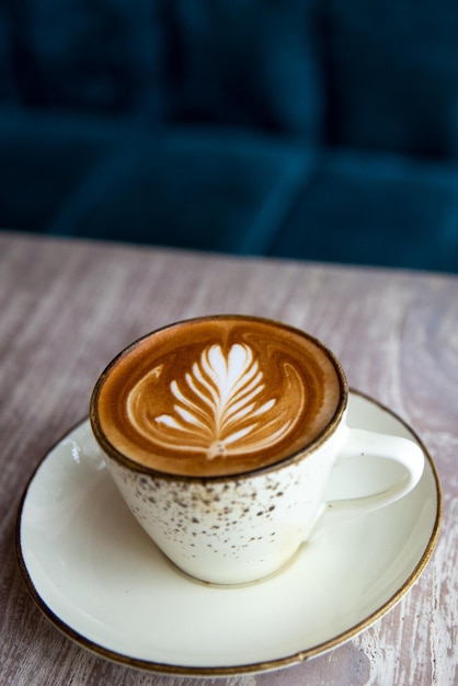 Hot cappuccino coffee cup with heart shape latte art on brown old wooden table at cafe