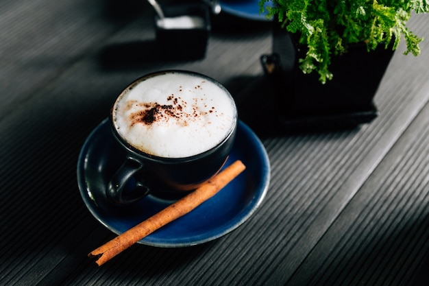 Hot cappuccino with cinnamon served in blue cup.