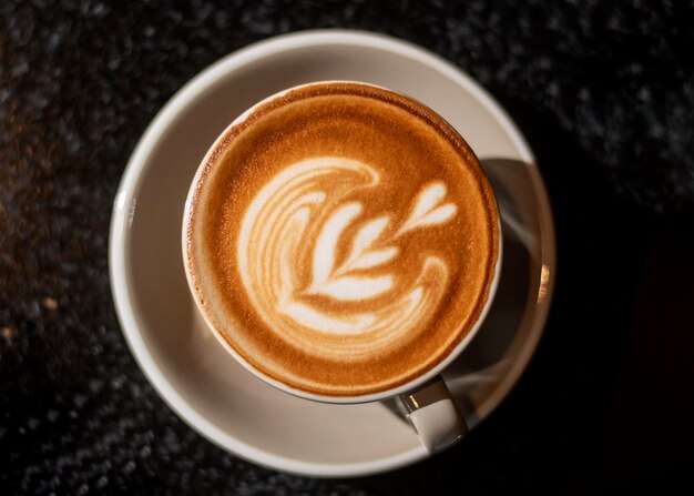 Hot cappuccino with latte art on wood background