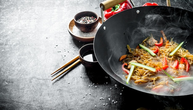 Hot cellophane noodles in a frying pan wok with bell peppers cucumber and carrots