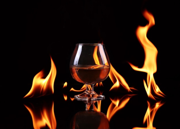 Hot chili pepper in a  cognac ballon with a fire on black