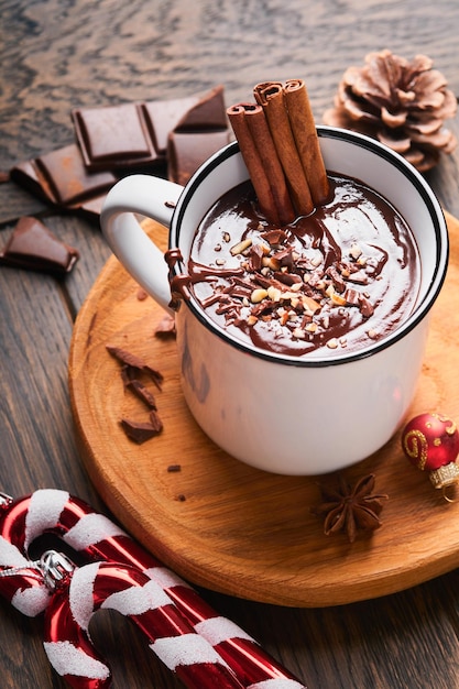 Hot chocolate Homemade spicy hot chocolate with cinnamon crushed hazelnut christmas decor and toys in enamel mug on old wooden background Christmas idea Cozy seasonal holidays