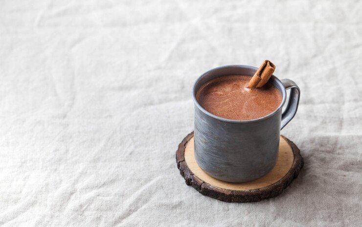 Photo テーブルクロスにシナモンスティックが付いた金属製マグカップのホットチョコレート。