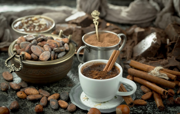 Hot chocolate on an old background in a composition with cocoa beans and nuts.