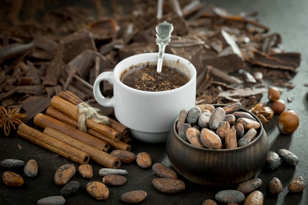 Горячий шоколад на старом фоне в композиции с какао-бобами и орехами.