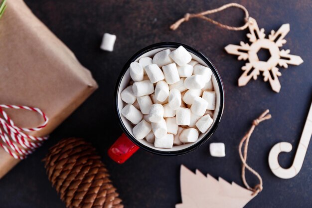 Foto cioccolata calda in una tazza rossa con marshmallow circondato da decorazioni natalizie