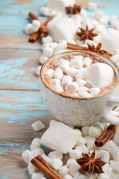 Hot Chocolate, White Marshmallows and Winter Spices on Blue Wooden Background 