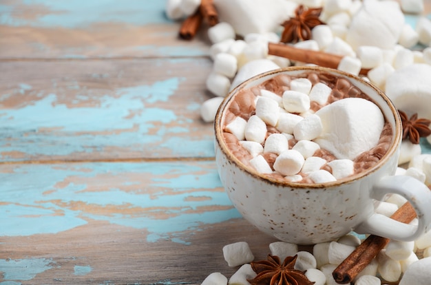 Hot Chocolate, White Marshmallows and Winter Spices on Blue Wooden Background 