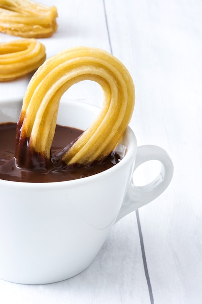 Hot chocolate with churros on white wood. Spanish breakfast