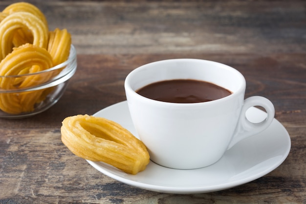 Hot chocolate with churros on wooden table Spanish breakfast