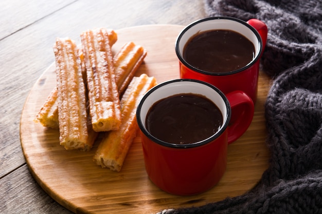 Cioccolata calda con churros sul tavolo di legno.