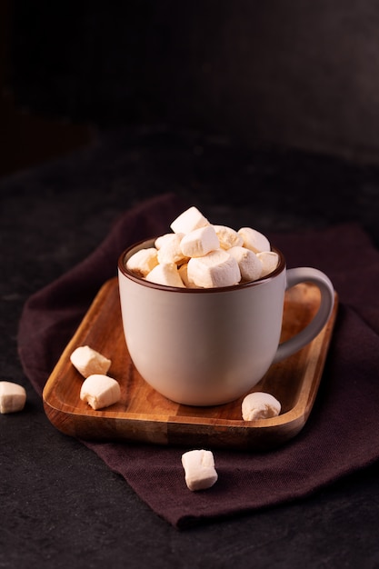 Cioccolata calda con cannella e marshmallow su sfondo scuro