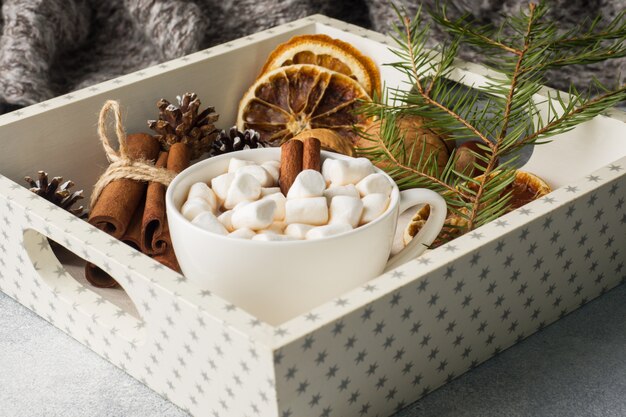 Hot chocolate with marshmallow cinnamon sticks, anise and nuts on wooden tray