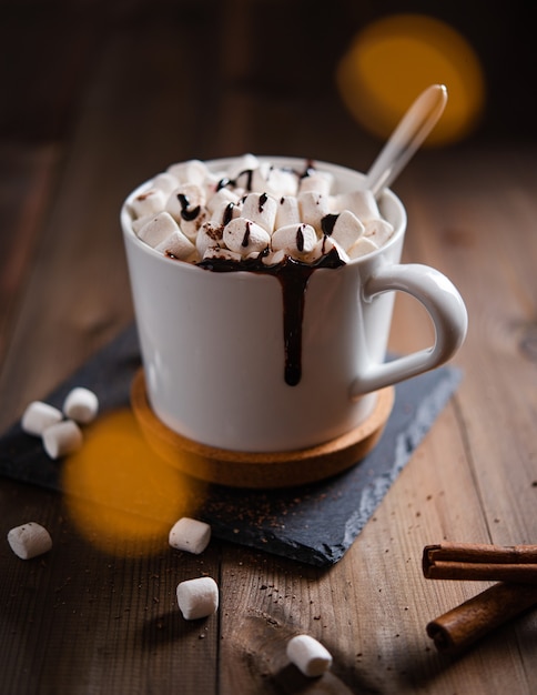 Hot chocolate with  marshmallow  in a white mug on a wooden table. Macro and close up view. Dark photo