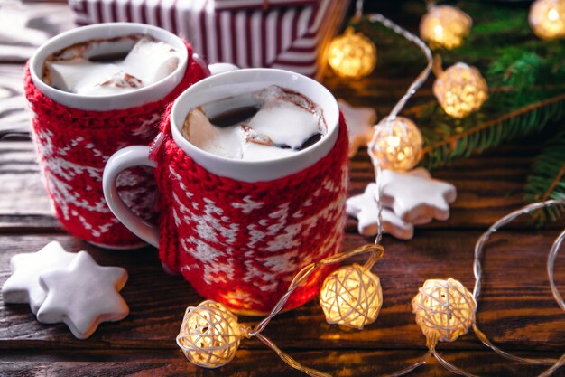 Hot chocolate with marshmallows and biscuits on Christmas decorations background.