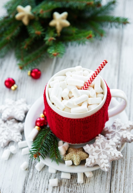 Hot chocolate with marshmallows and gingerbread cookie on a old wooden table