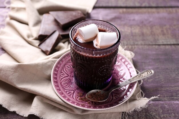 Hot chocolate with marshmallows in glass, on color wooden table