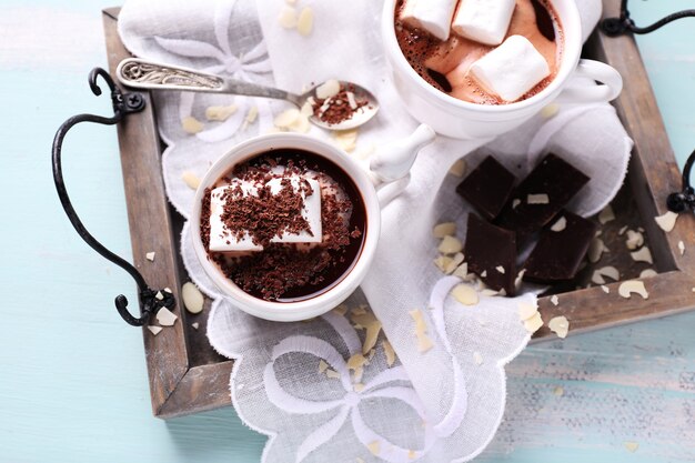 Hot chocolate with marshmallows in mug, on tray, on color wooden background