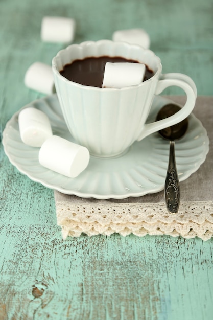 Hot chocolate with marshmallows in mug, on wooden background