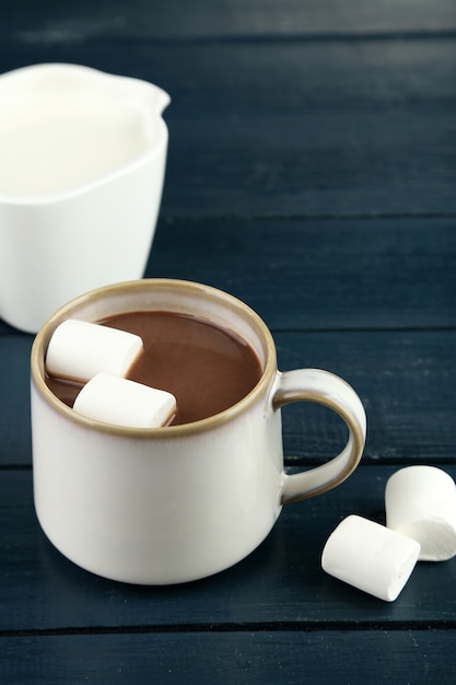 Hot chocolate with marshmallows in mug, on wooden surface