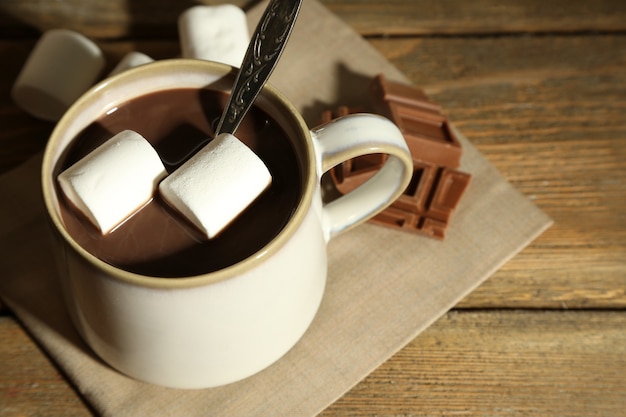 Hot chocolate with marshmallows in mug, on wooden surface