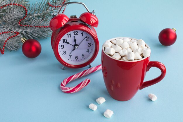 Hot chocolate with marshmallows in the red cup amd red alarm clock