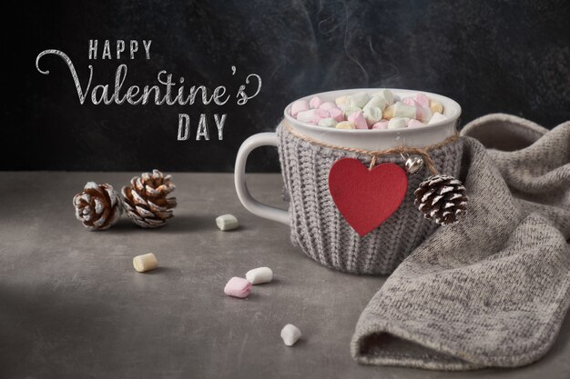 Hot chocolate with marshmallows, red heart on the cup on the table